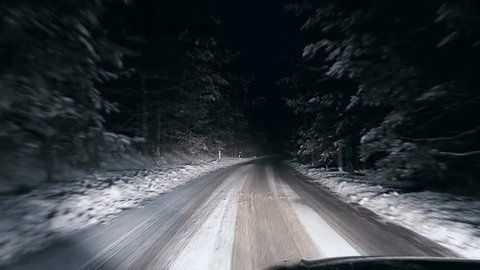 Bilk白ameravy av snötäckt skogsväg i mörker under vinterkörning