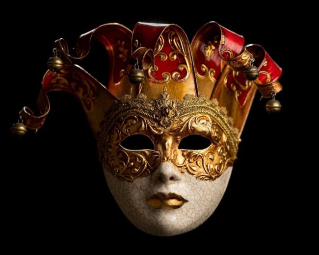 Utsmyckad röd och guldfärgad maskeradmask mot svart bakgrund